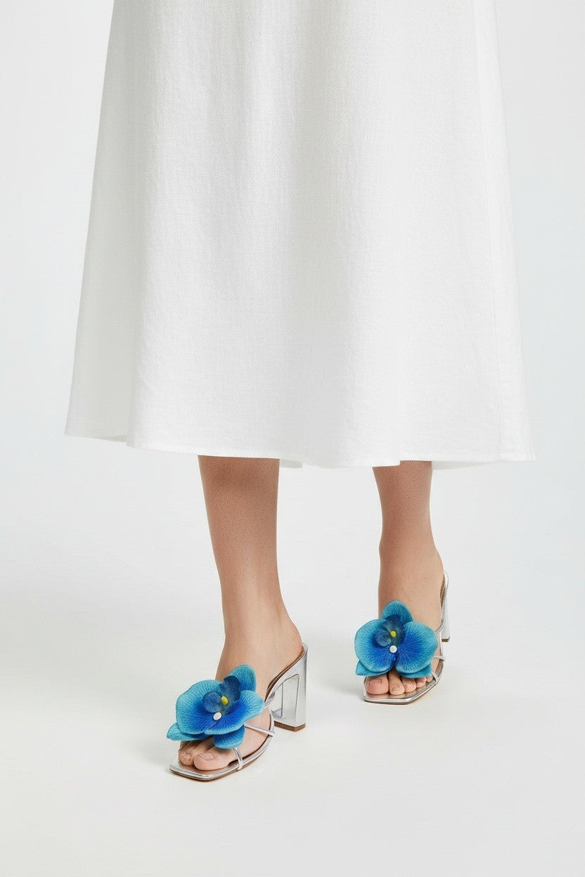 Silver slip-on sandal heels with blue silk orchid flower accents.