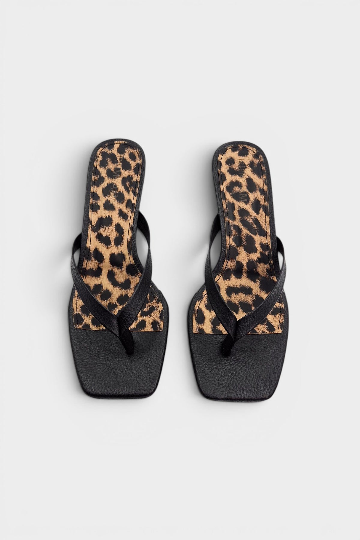 Black thong sandal mules with cheetah print insoles and kitten heels.