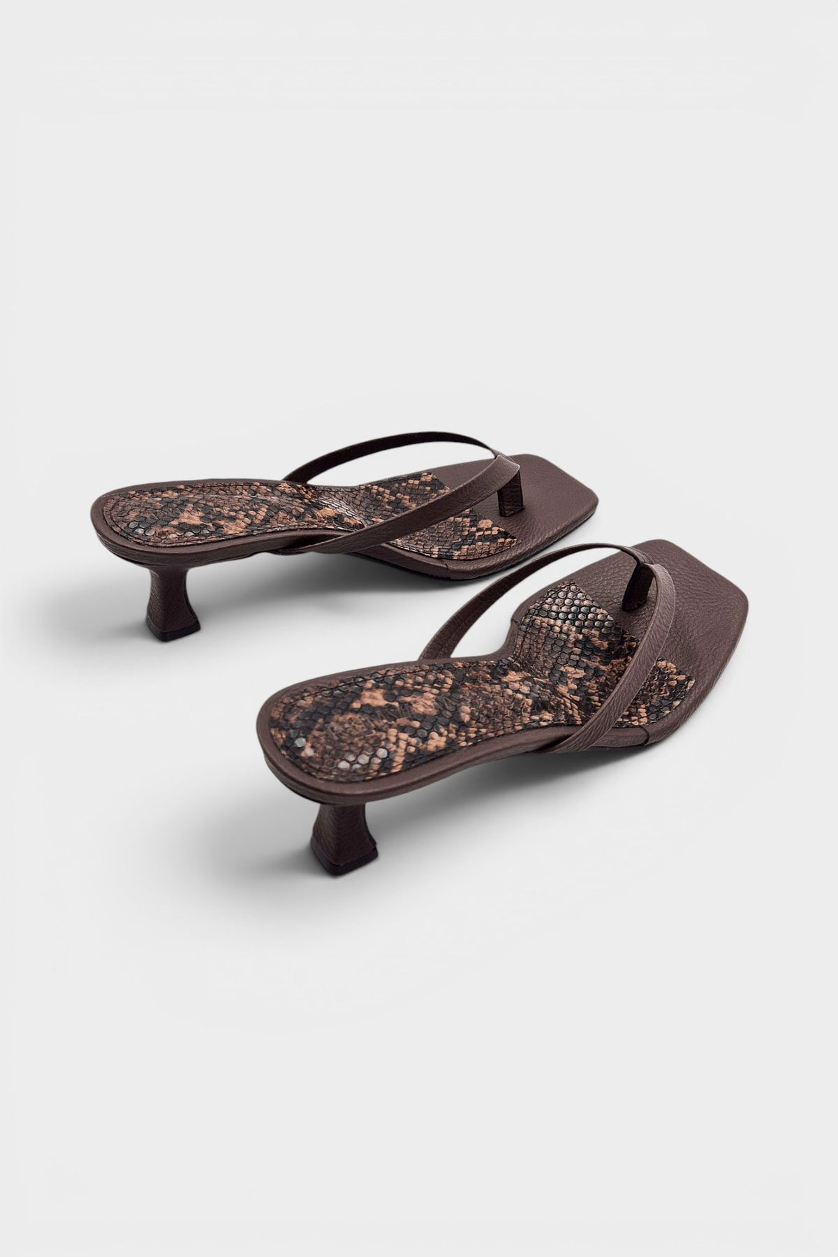 Brown thong sandal mules with snake print insoles and kitten heels.
