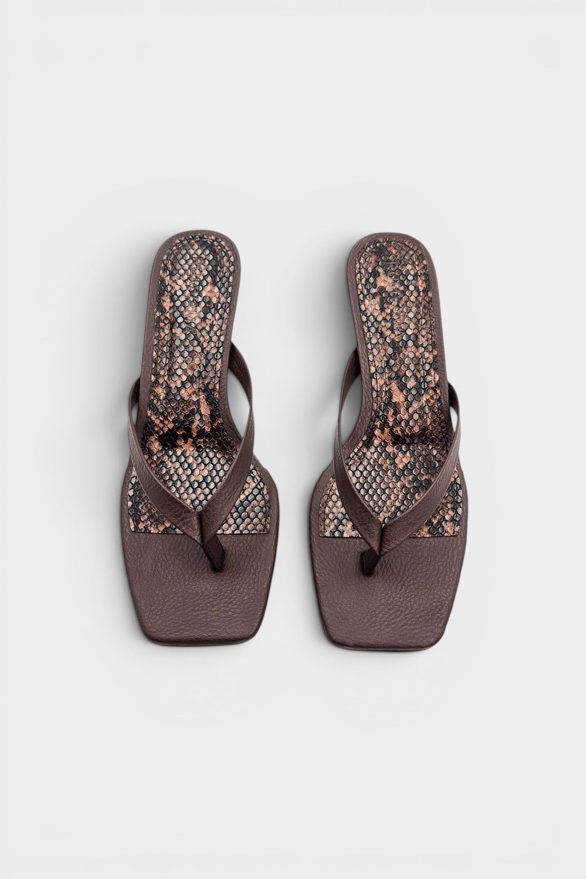 Brown thong sandal mules with snake print insoles and kitten heels.