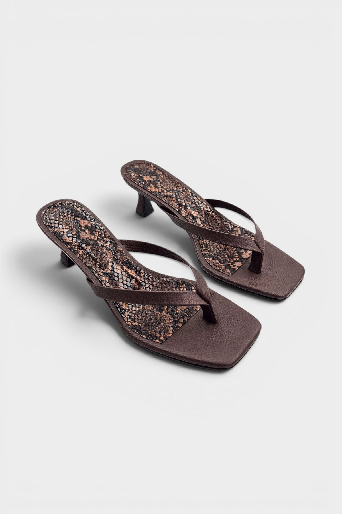 Brown thong sandal mules with snake print insoles and kitten heels.